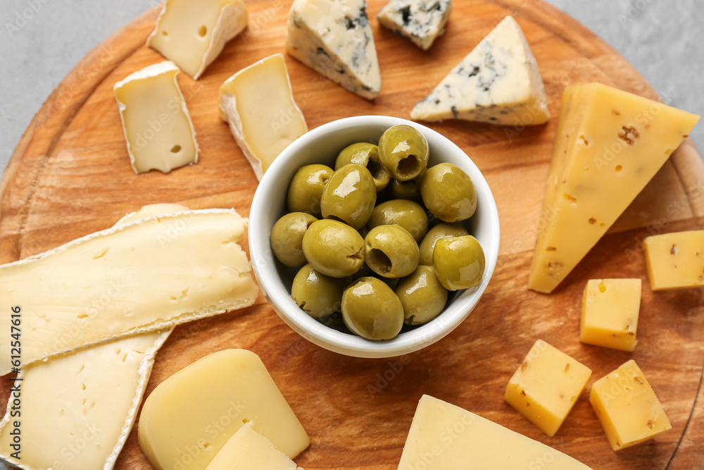 Wooden board with pieces of tasty cheese on table