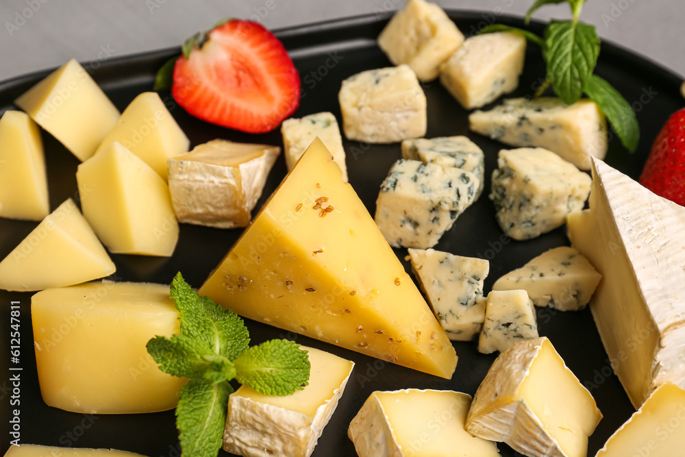 Tray with pieces of tasty cheese on table, closeup