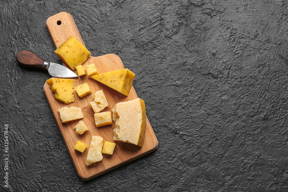 Wooden board with pieces of tasty cheese on dark background