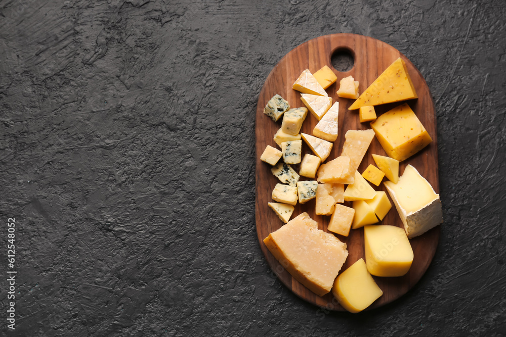 Board with pieces of tasty cheese on dark background