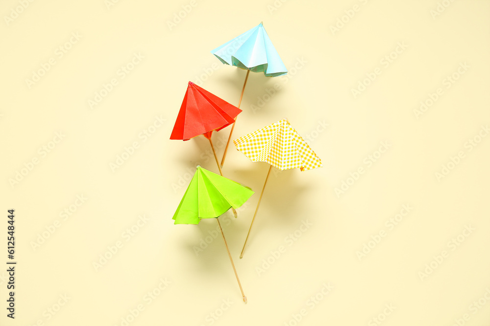 Different mini umbrellas on pale yellow background