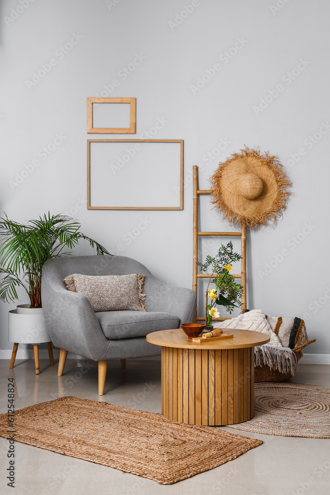 Interior of living room with ikebana on table and armchair