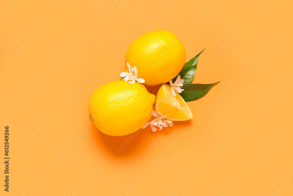 Lemons with leaves and flowers on orange background