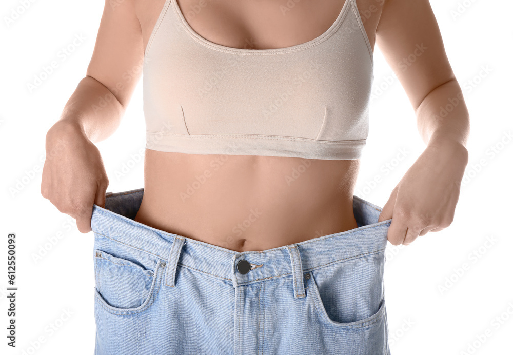 Young woman in loose jeans on white background. Diet concept