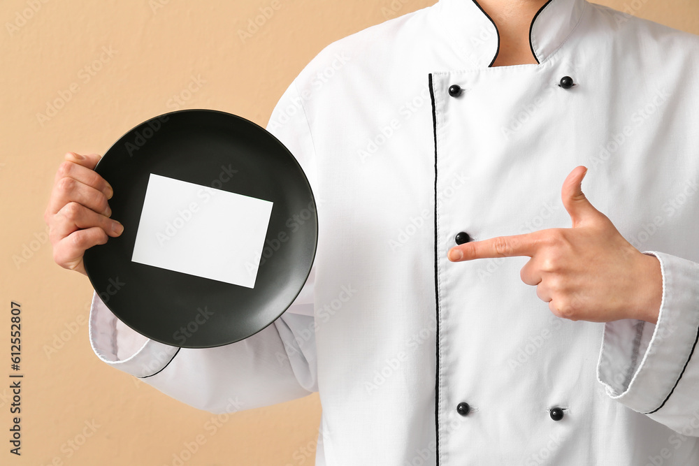 Female chef holding plate with blank card on beige background, closeup