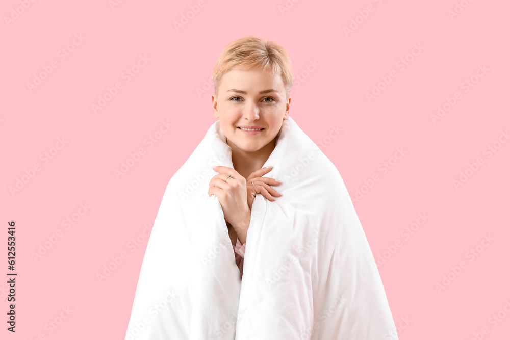 Young woman with soft blanket on pink background