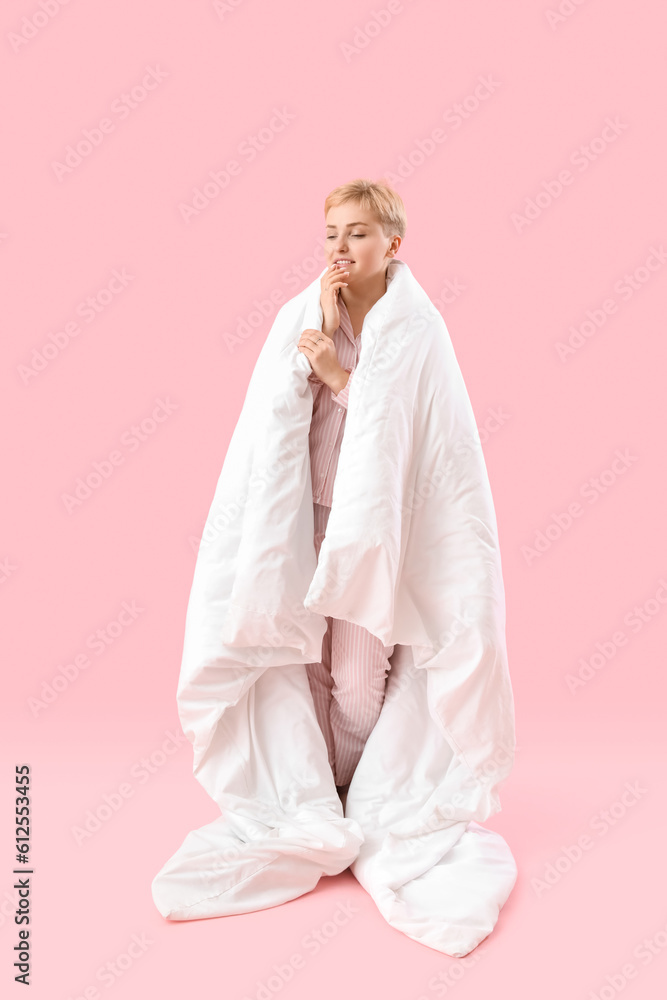 Young woman with soft blanket on pink background