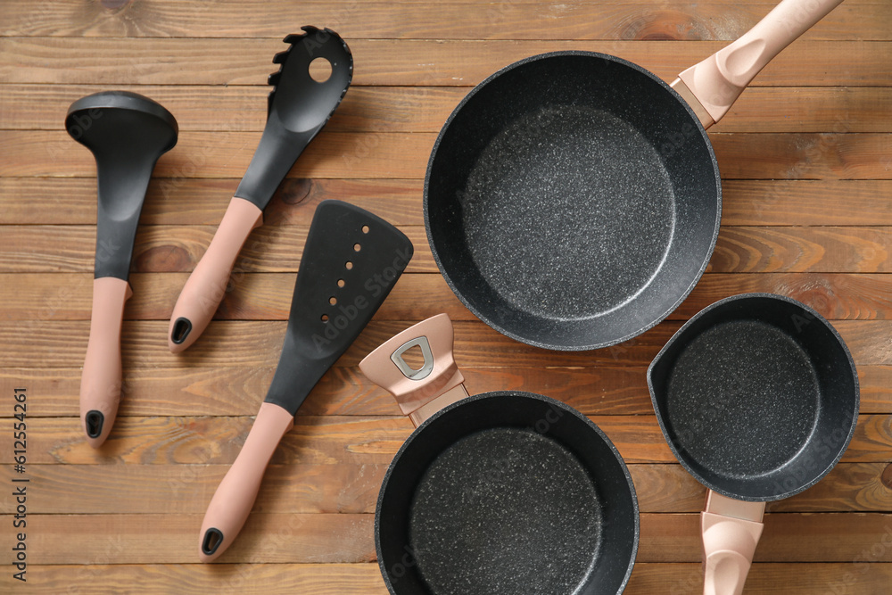 Cooking pot, frying pans and kitchen utensils on wooden background