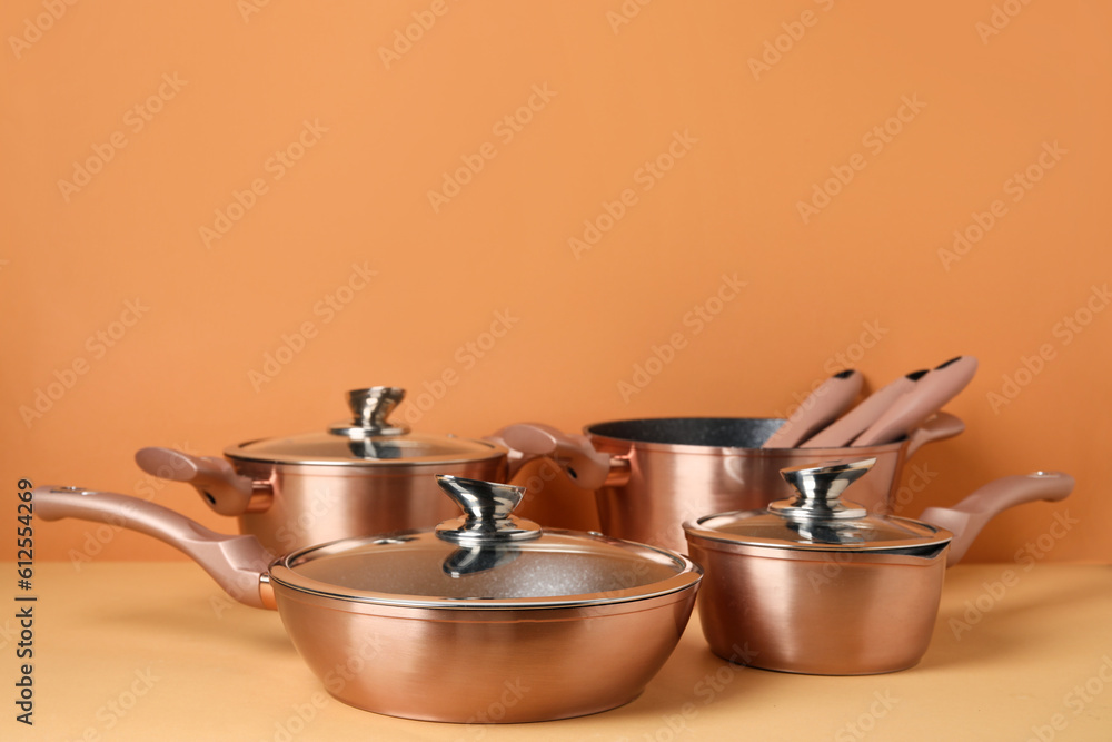 Set of copper kitchen pots and kitchen utensils on color background