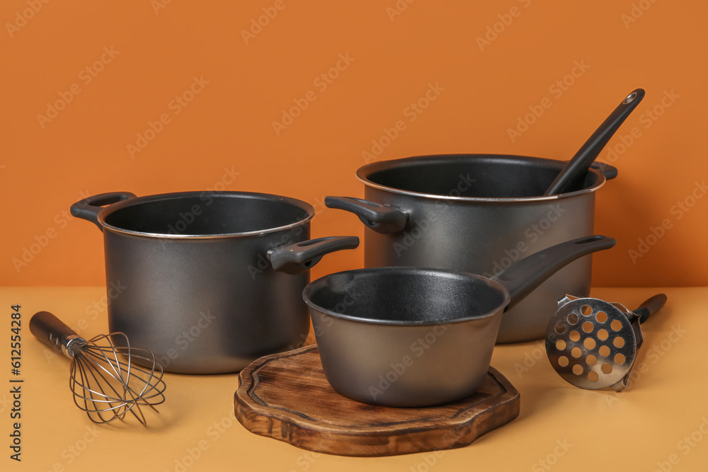 Set of kitchen pots and kitchen utensils on color background