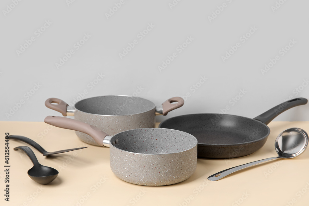 Cooking pots, frying pan and kitchen utensils on color background