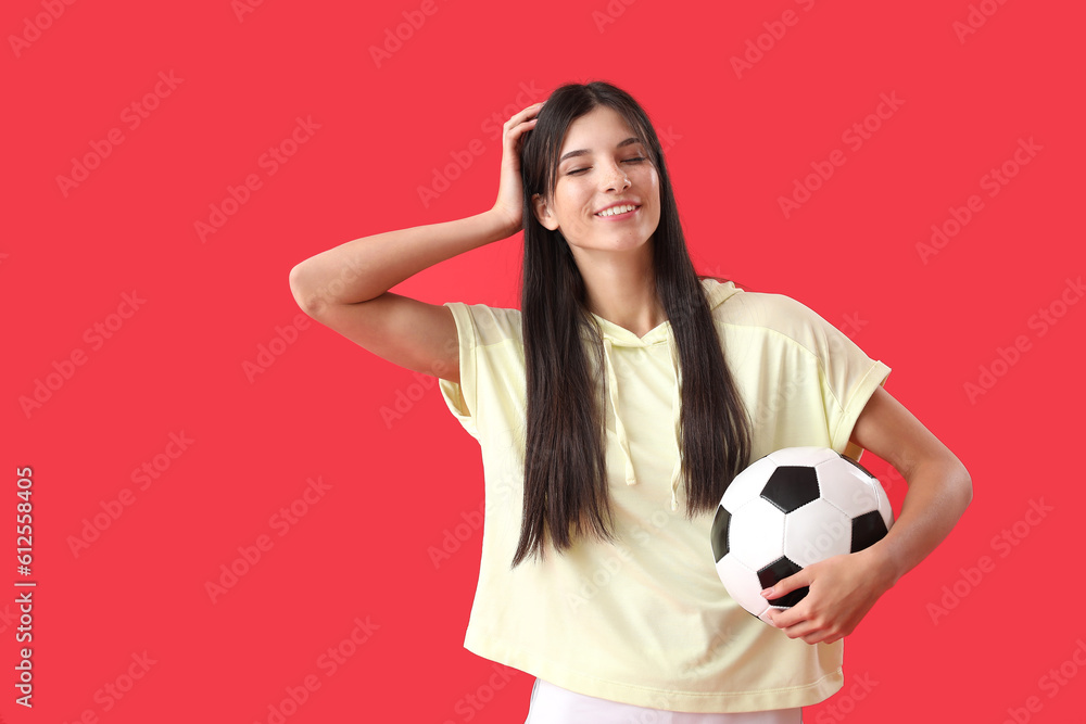 Young woman with soccer ball on red background