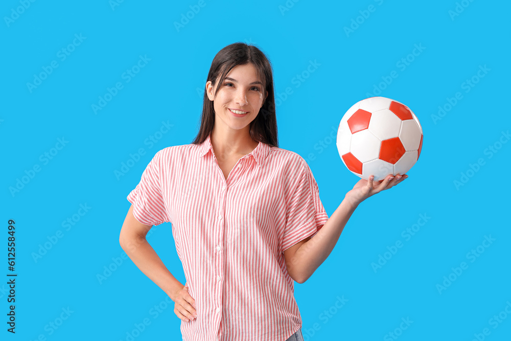 Young woman with soccer ball on blue background