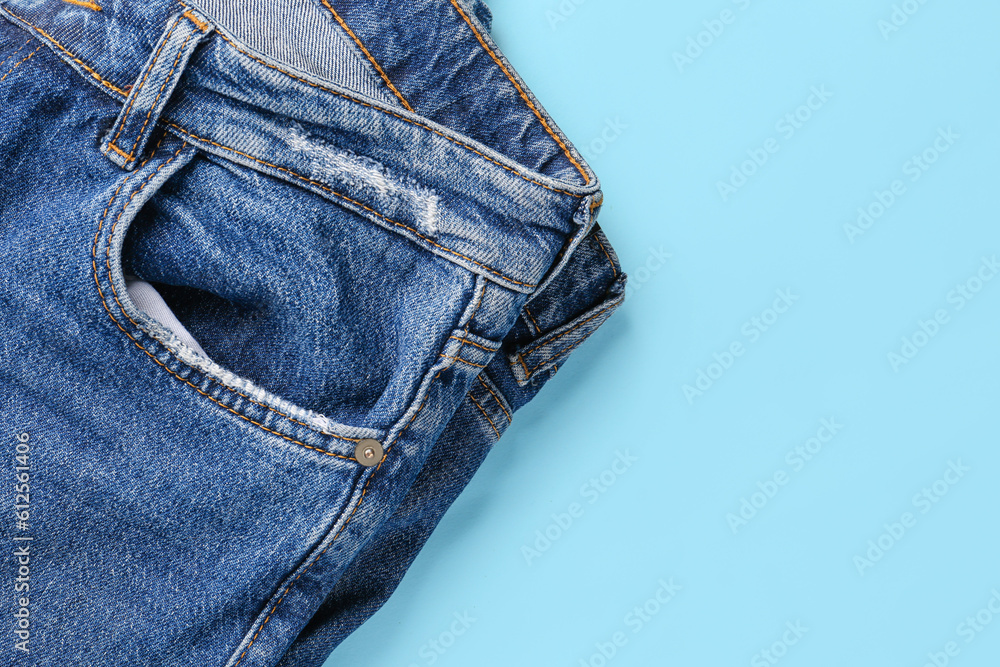 Stylish denim jeans on blue background, closeup