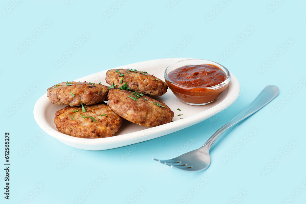 Cutlets with chopped parsley, ketchup and fork on blue background