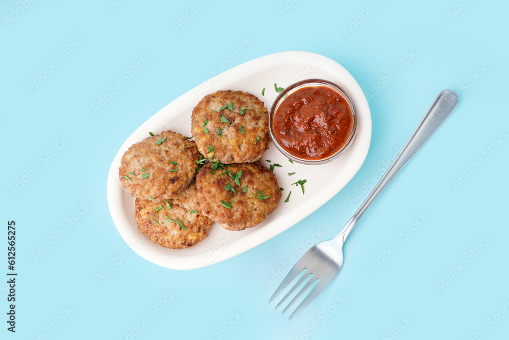 Cutlets with chopped parsley, ketchup and fork on blue background