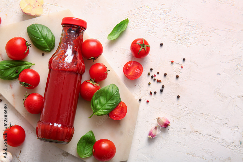 Board with glass bottle of ketchup and tomatoes on white background