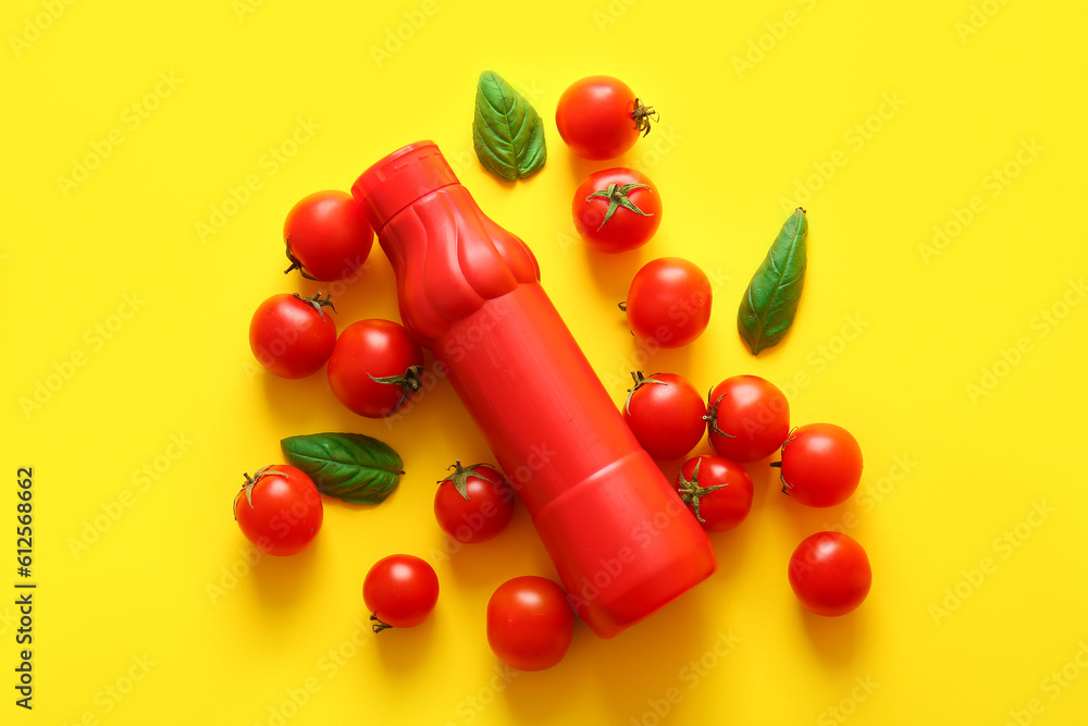 Bottle of ketchup and tomatoes on yellow background