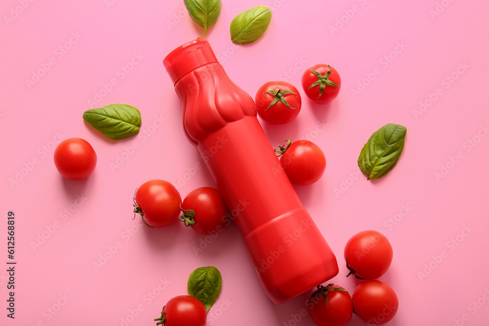 Bottle of ketchup and tomatoes on pink background