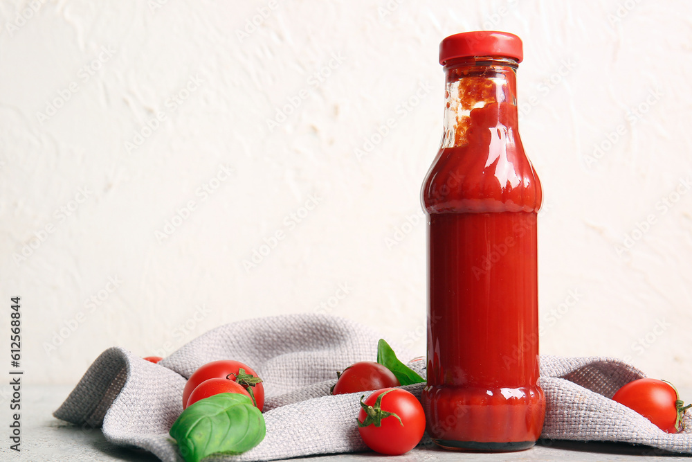 Glass bottle of ketchup and tomatoes on white background