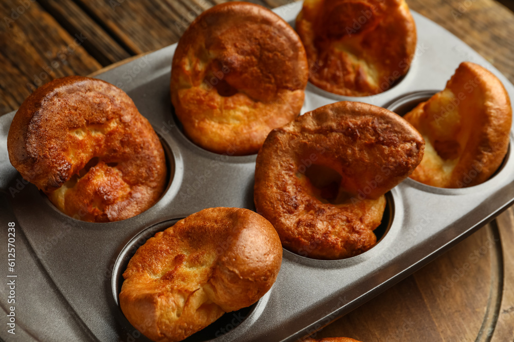 Baking tin with tasty Yorkshire pudding on wooden background