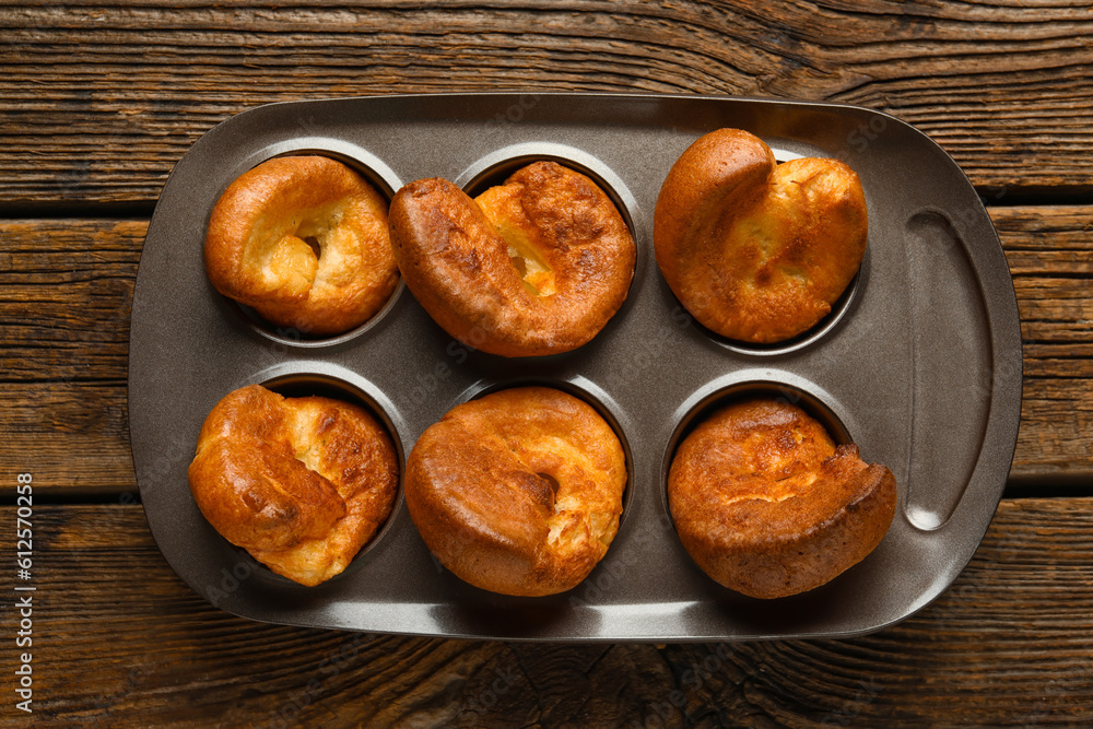 Baking tin with tasty Yorkshire pudding on wooden background