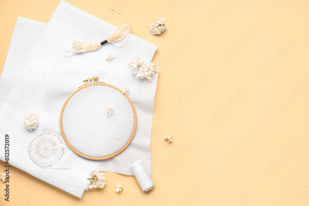 Wooden embroidery hoop with canvases and ball pins on pale orange background