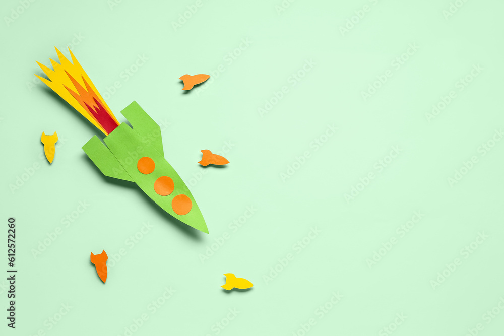 Colorful paper rockets on pale green background