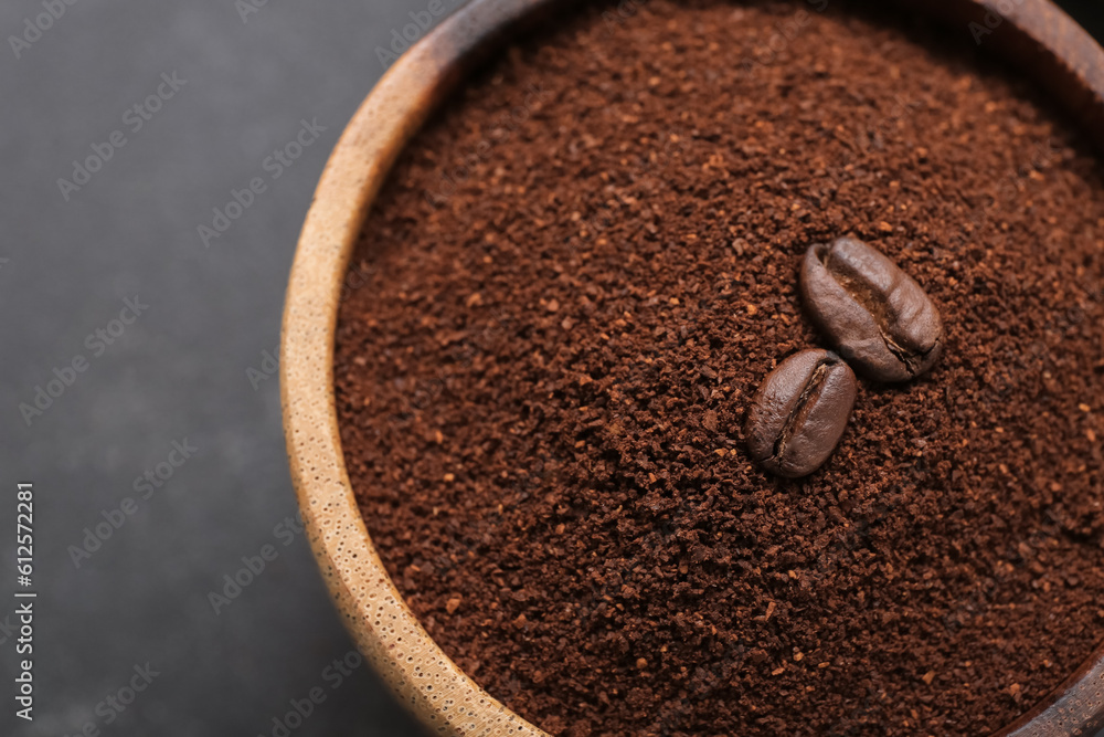 Bowl with coffee powder and beans on dark background