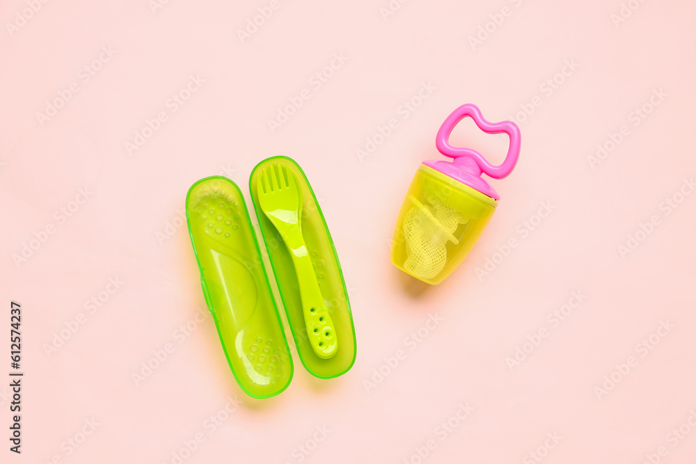 Eating utensils with nibbler for baby on pink background