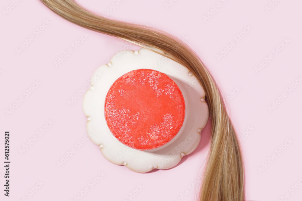 Red solid shampoo bar with hair on pink background