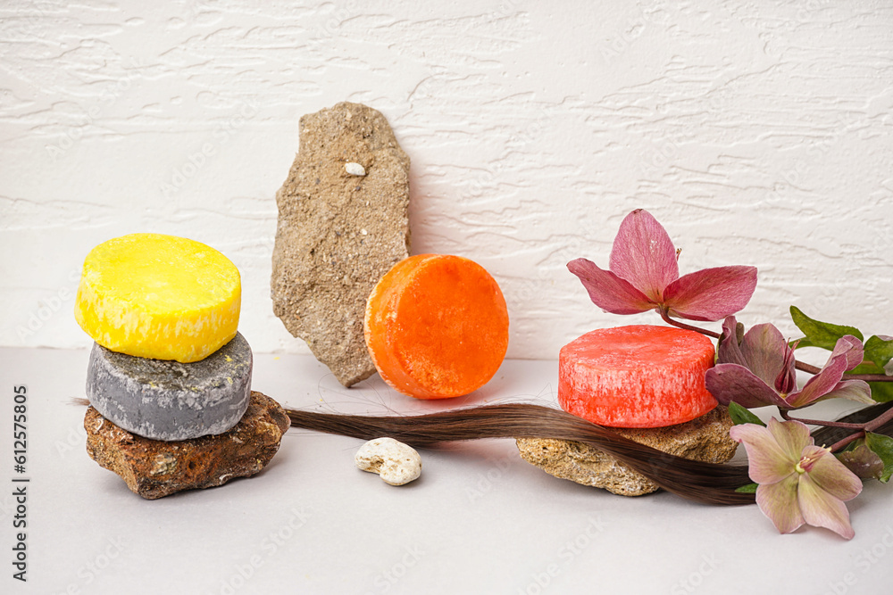 Solid shampoo bars with stones, hair and flowers on table