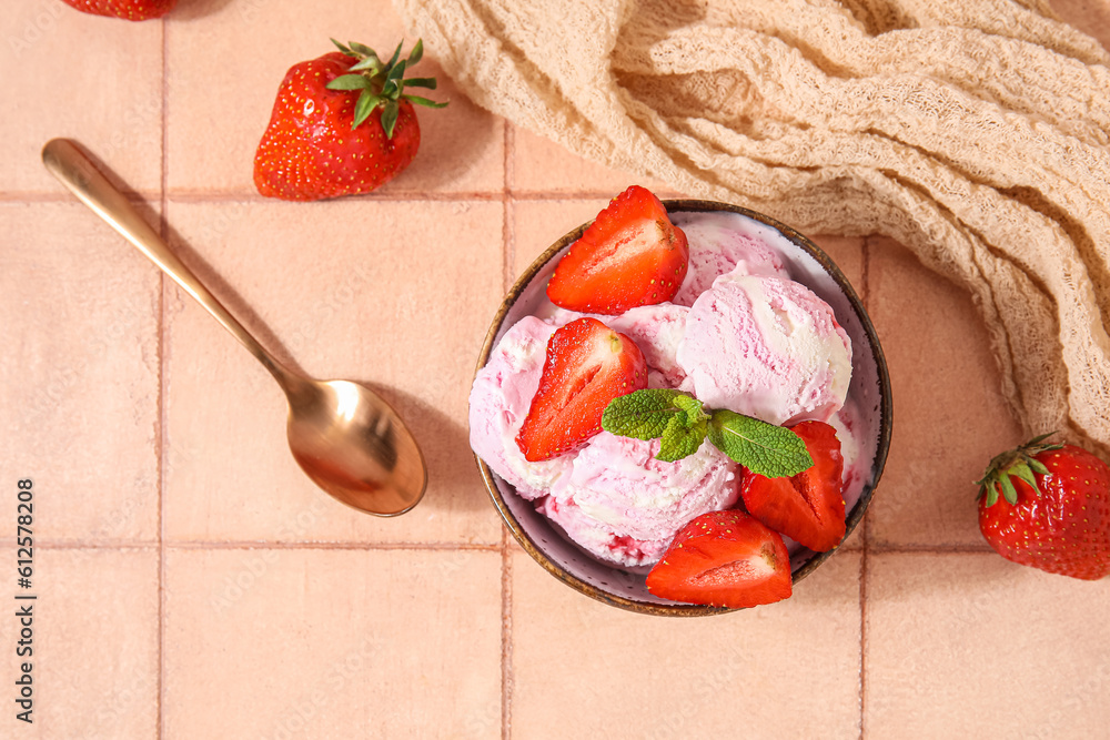 Bowl of strawberry ice cream with berries, mint and spoon on beige tile table