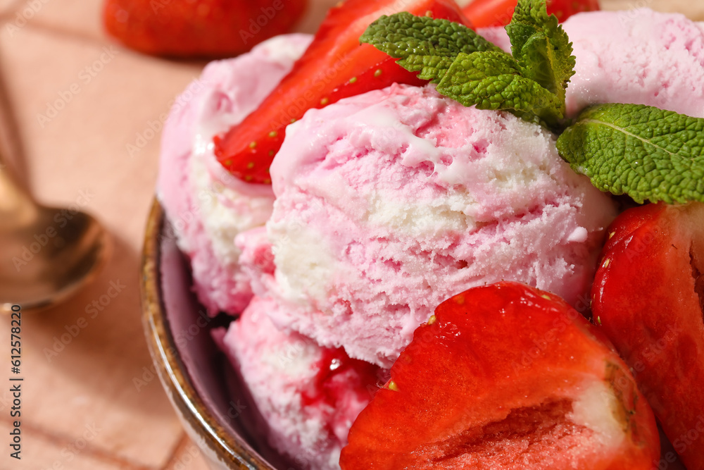 Bowl of strawberry ice cream with berries and mint on table, closeup