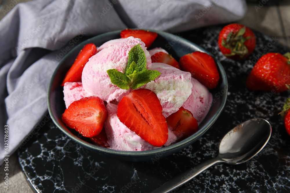 Bowl of strawberry ice cream with berries, mint and spoon on table, closeup