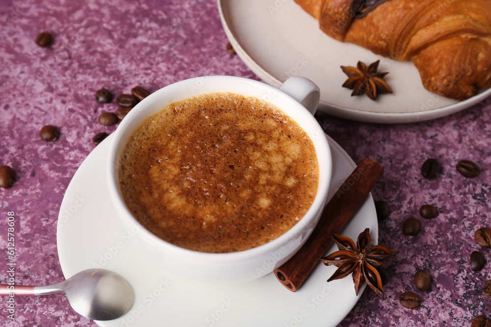 Cup of delicious espresso with coffee beans and croissant on purple background, closeup