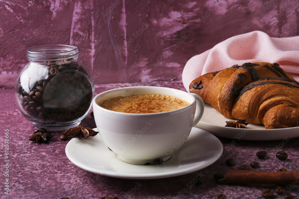 Cup of delicious espresso with coffee beans and croissant on purple background, closeup