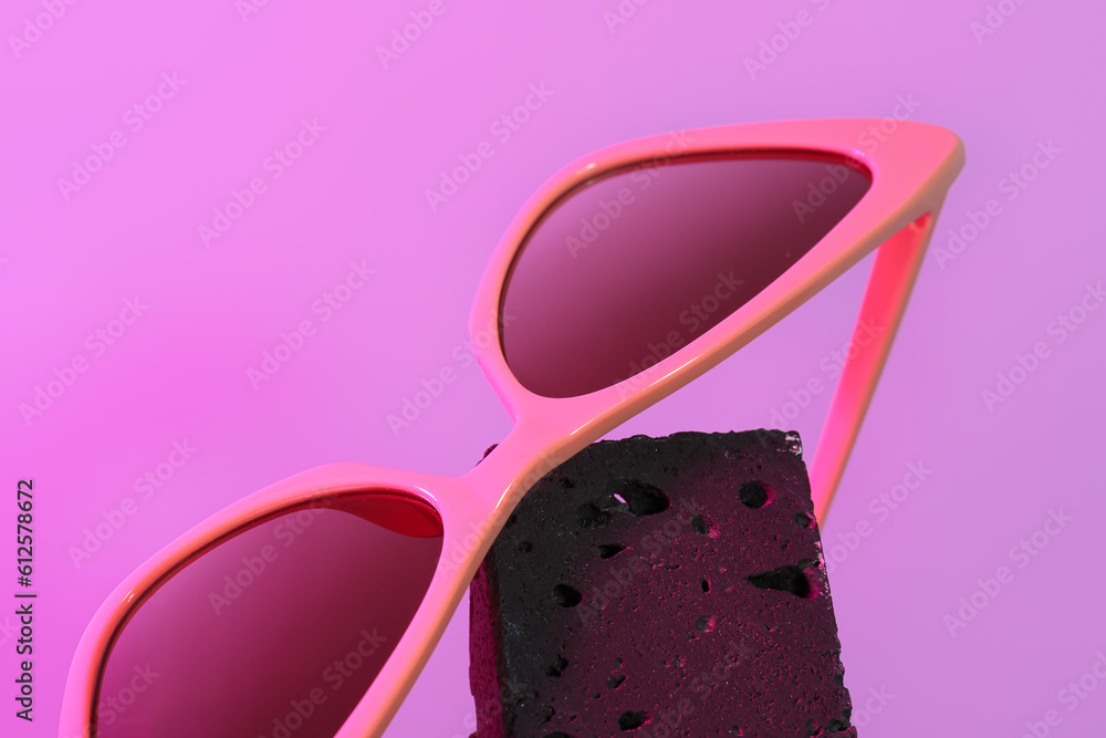 Stylish sunglasses on purple background, closeup