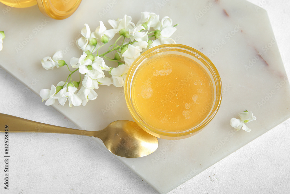 Bowl of honey with flowers of acacia on light background, closeup