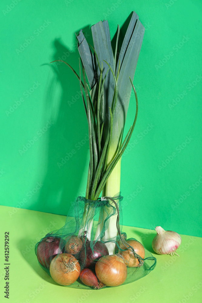 Eco bag with different kinds of onion on green background