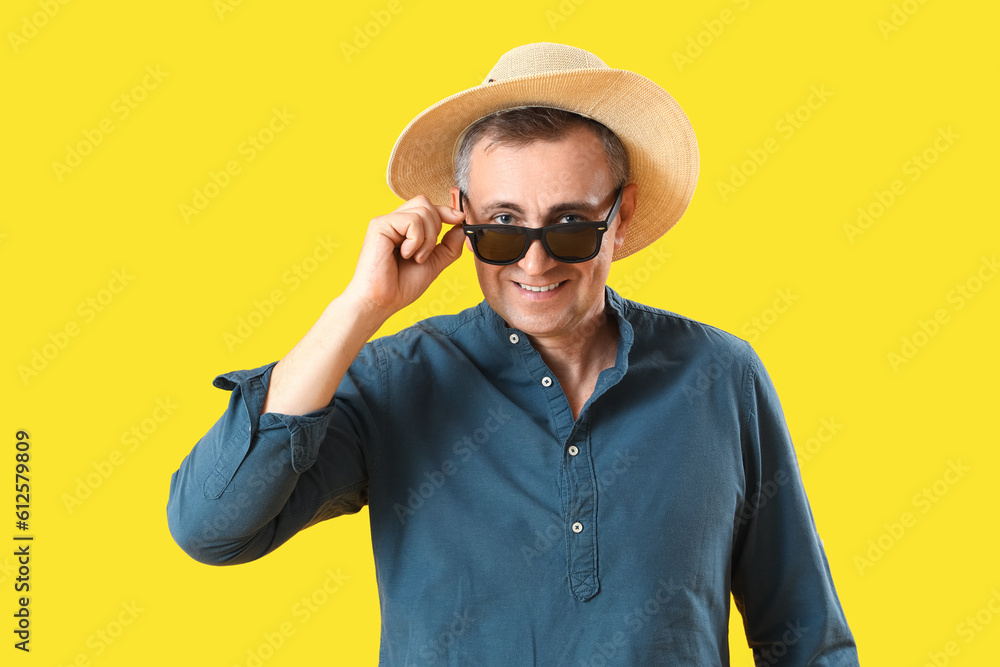 Mature man in sunglasses on yellow background