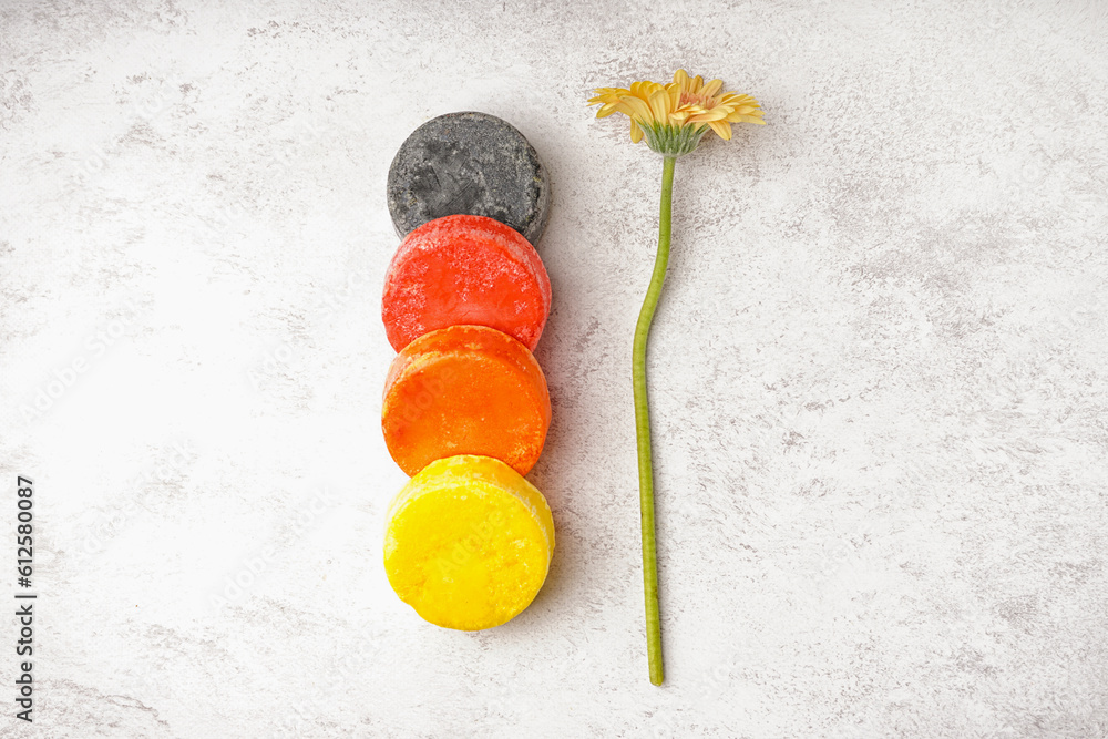 Different handmade solid shampoo and calendula flower on light background