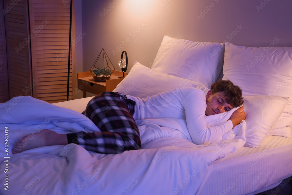 Young man sleeping in bed at night