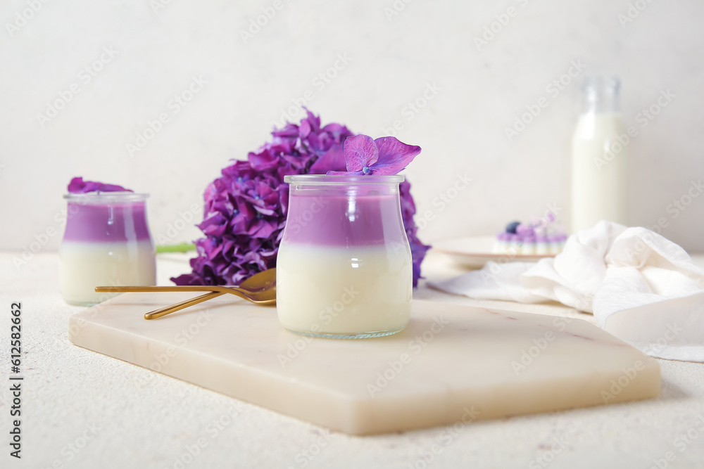 Glasses of panna cotta with beautiful hydrangea flowers on white table