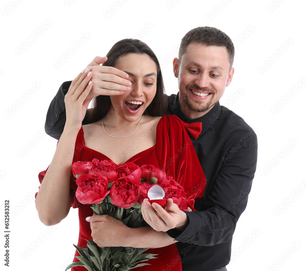 Young man with engagement ring closing his girlfriends eyes on white background