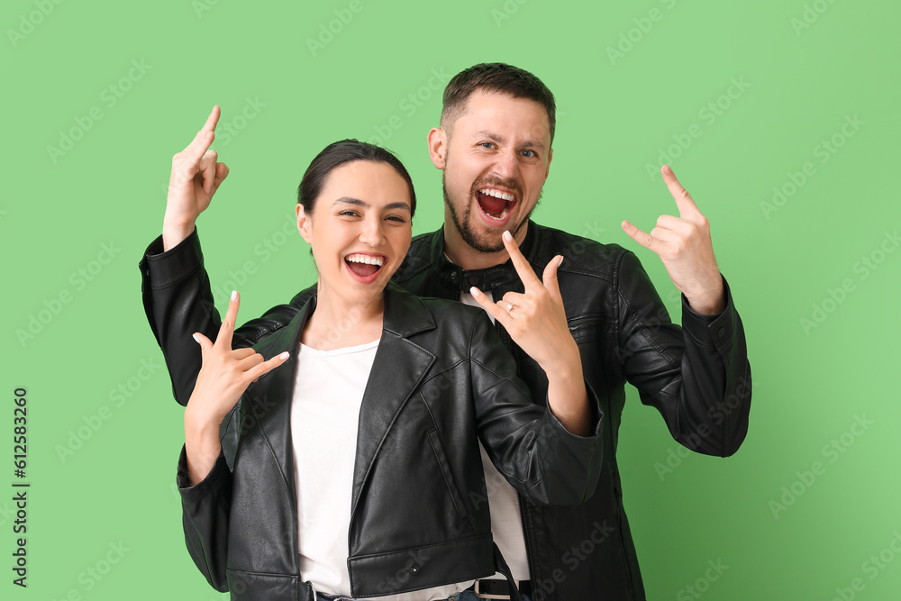 Engaged couple showing  devil horns  on green background