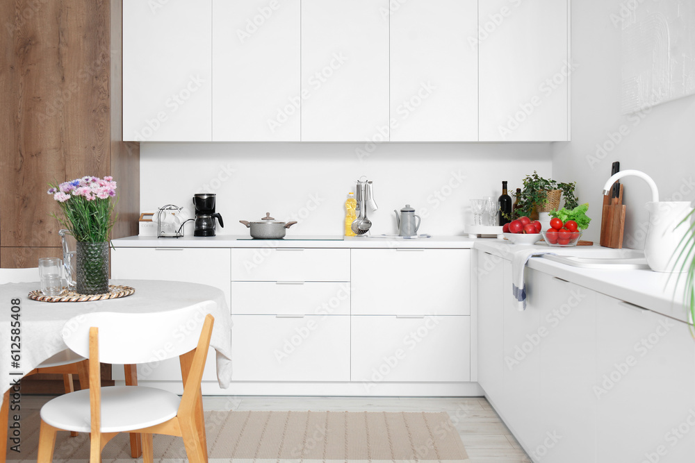 Interior of modern kitchen with flowers on dining table