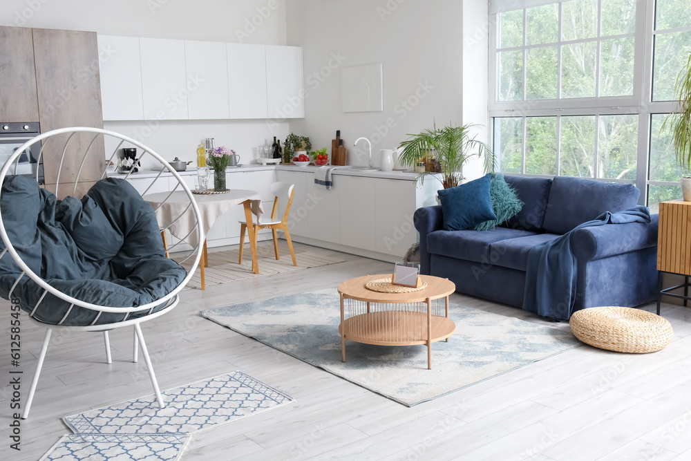 Interior of modern open plan kitchen with stylish sofa, armchair and coffee table