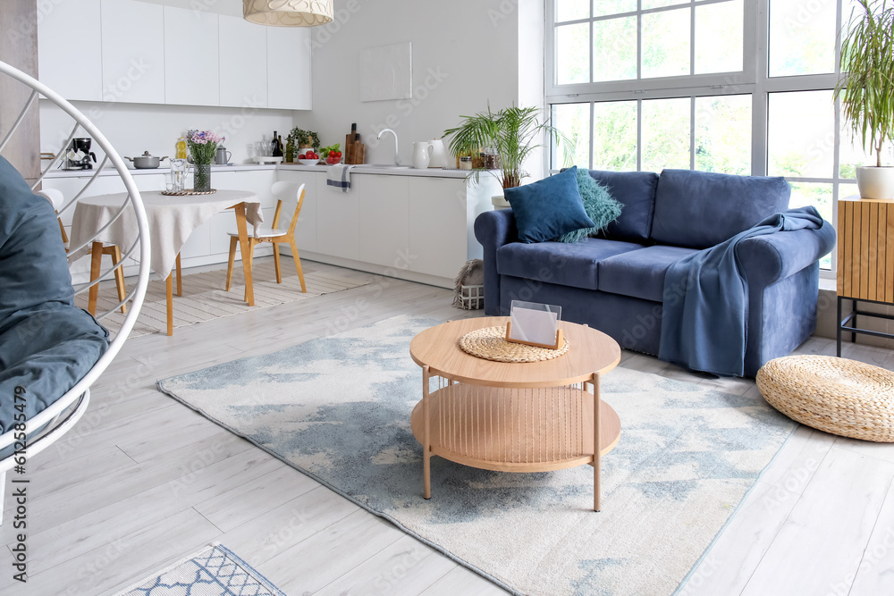 Interior of modern open plan kitchen with stylish sofa and coffee table