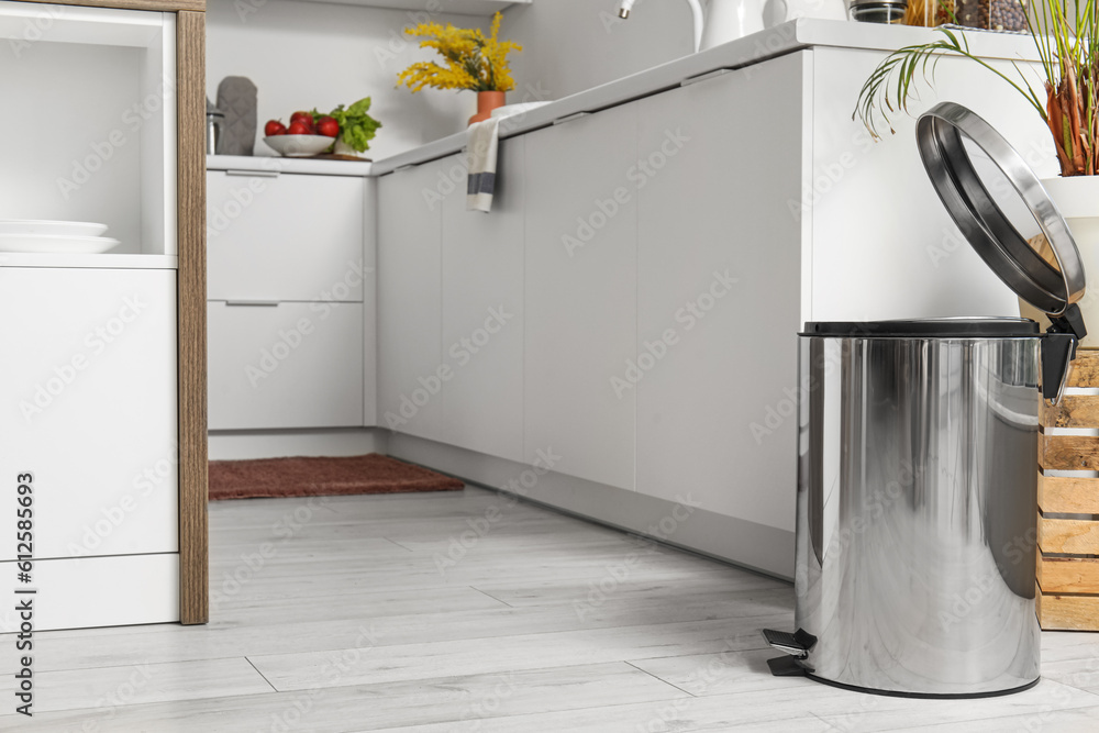 Opened metallic trash bin in interior of modern kitchen